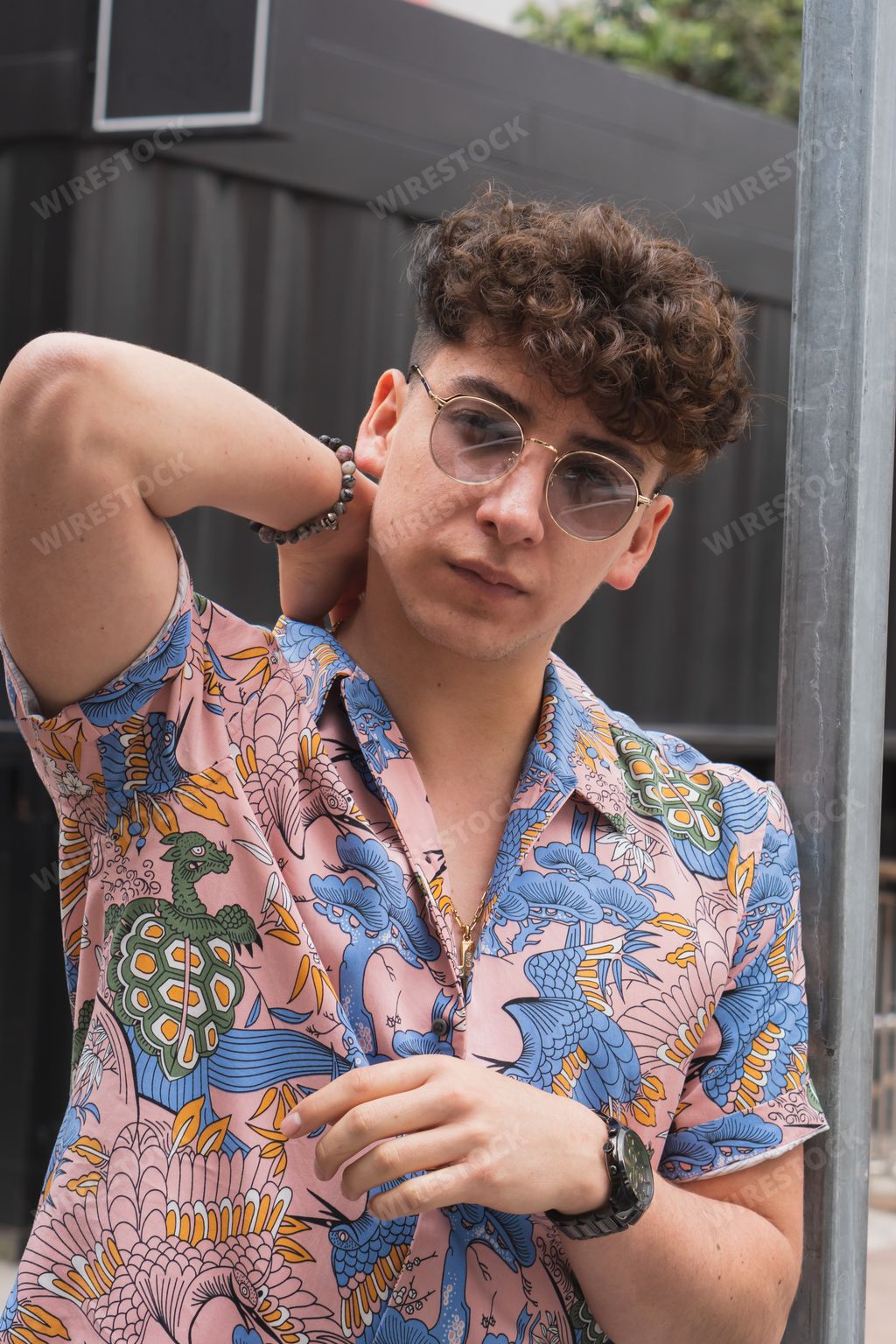 A young sexy Latino man with sunglasses and curly hair outdoors