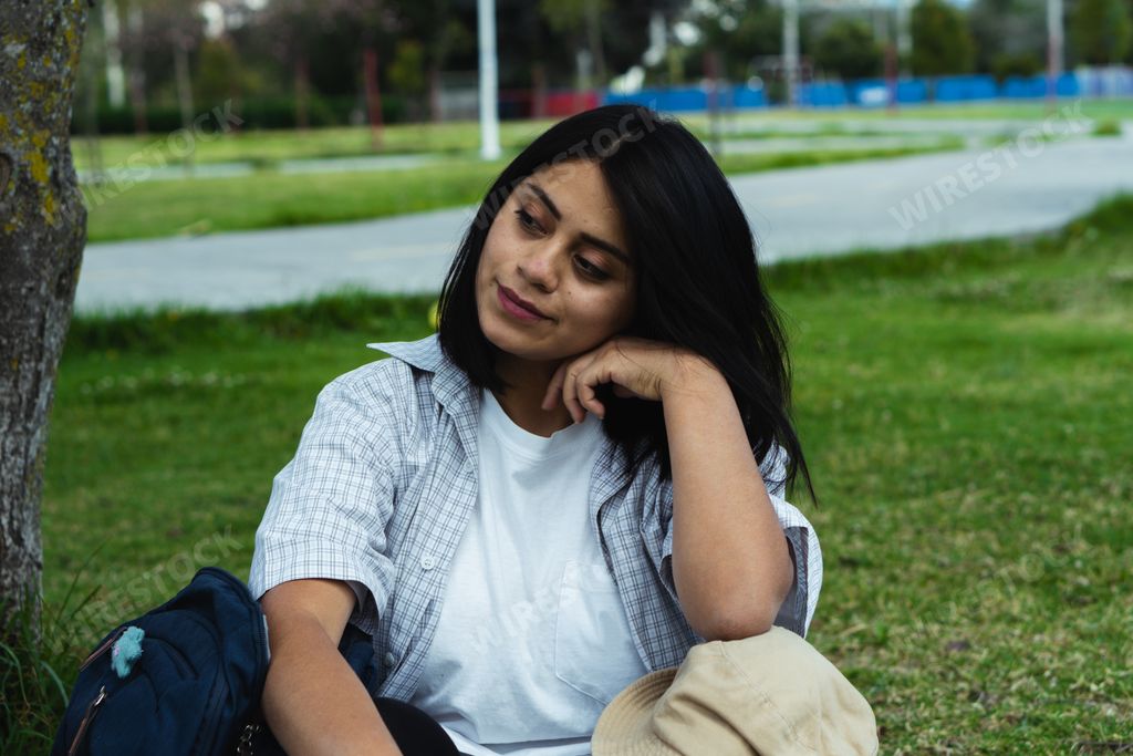 A Caucasian female student preparing to read an e-book in the park