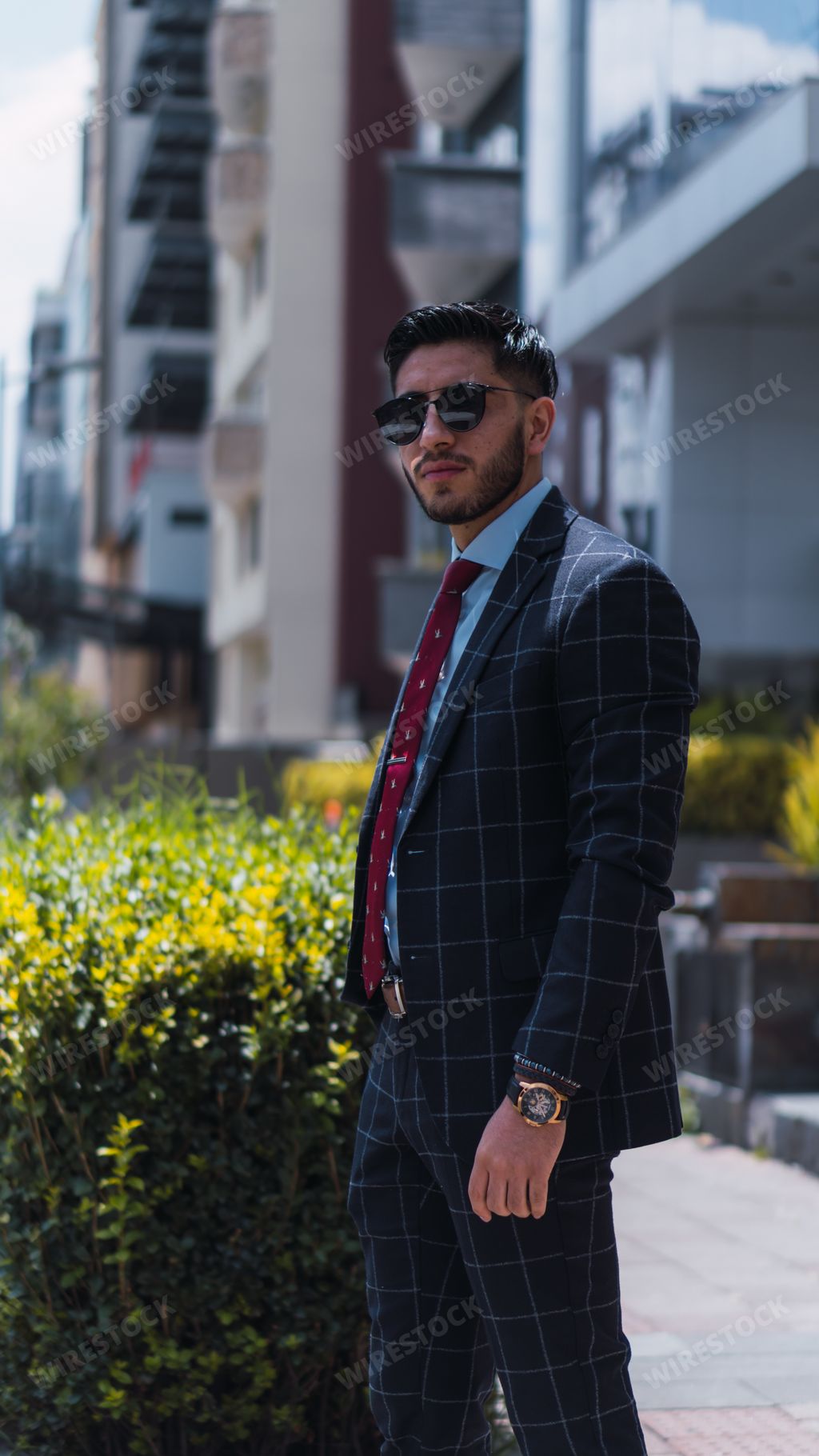 A shallow focus shot of a handsome male in elegant checkered suit and sunglasses