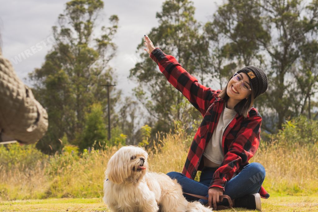 A young Hispanic woman walking with her pet dog through nature