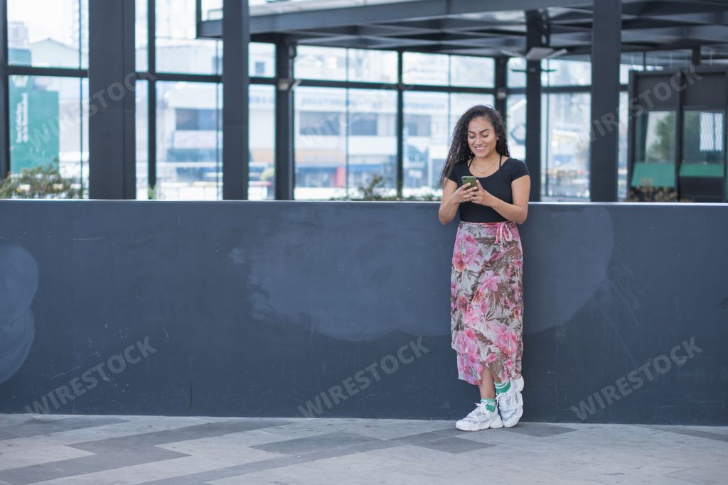 A Hispanic young female in the city calling by phone