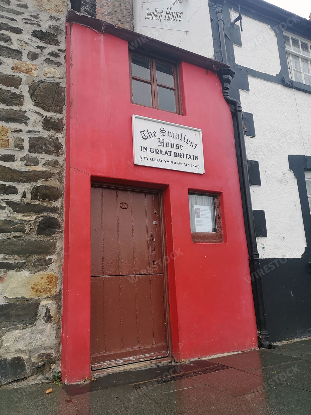 A facade of a house with a red door and brick stone walls in Great Britain at Conwy, North Wales, UK