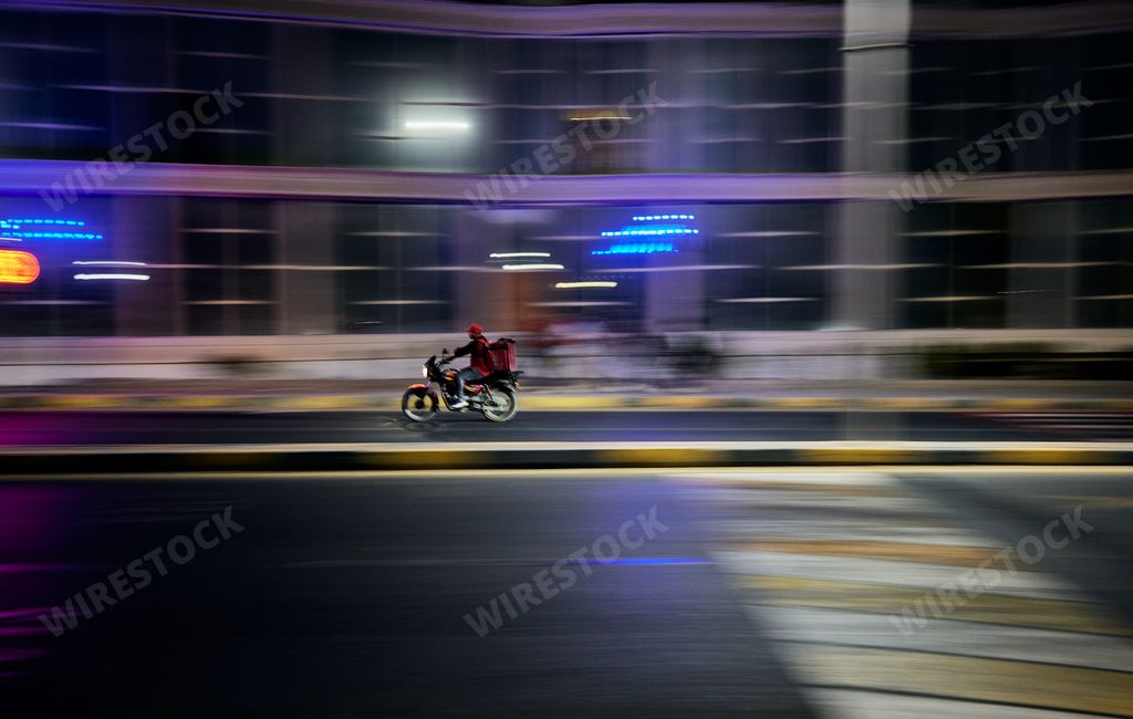Motorcycle driving on rainy city street at night