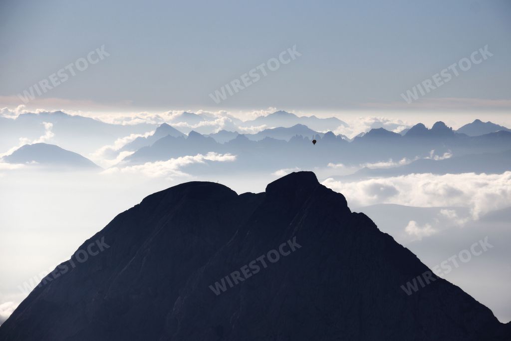 An awe-inspiring view of a hot air balloon taking off from a snow-covered mountain peak in the Bavarian Alps in Germany