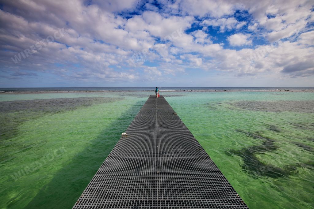 A person standing on a metal boardwalk on a sea in Mahahual, Quintana Roo, Mexico