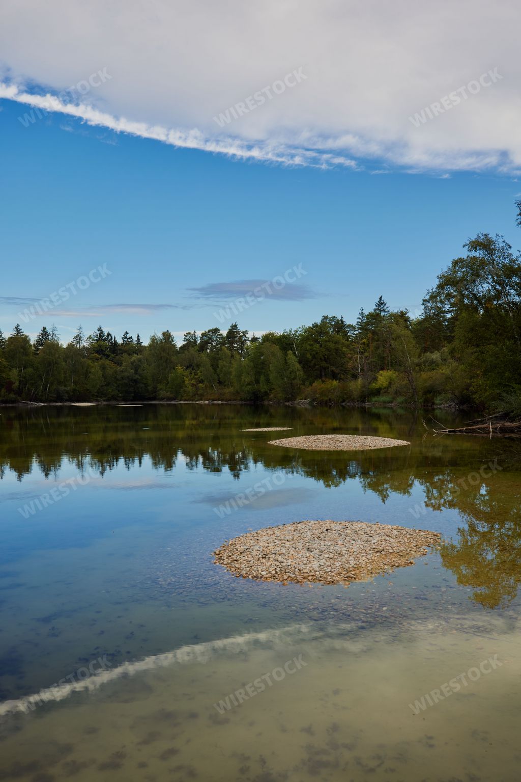 A vertical shot of a picturesque lake in Moos with the reflection of blue cloudy sky, Bavaria, Germany
