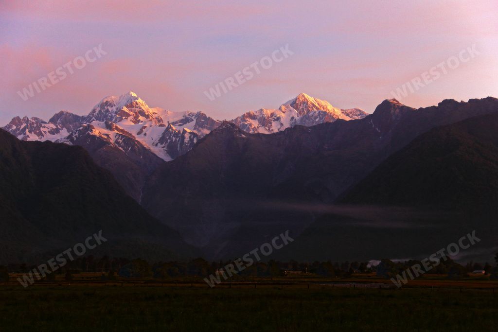 A stunning view of a mountain range with the sun setting in the background, emitting vibrant oranges and reds throughout the sky