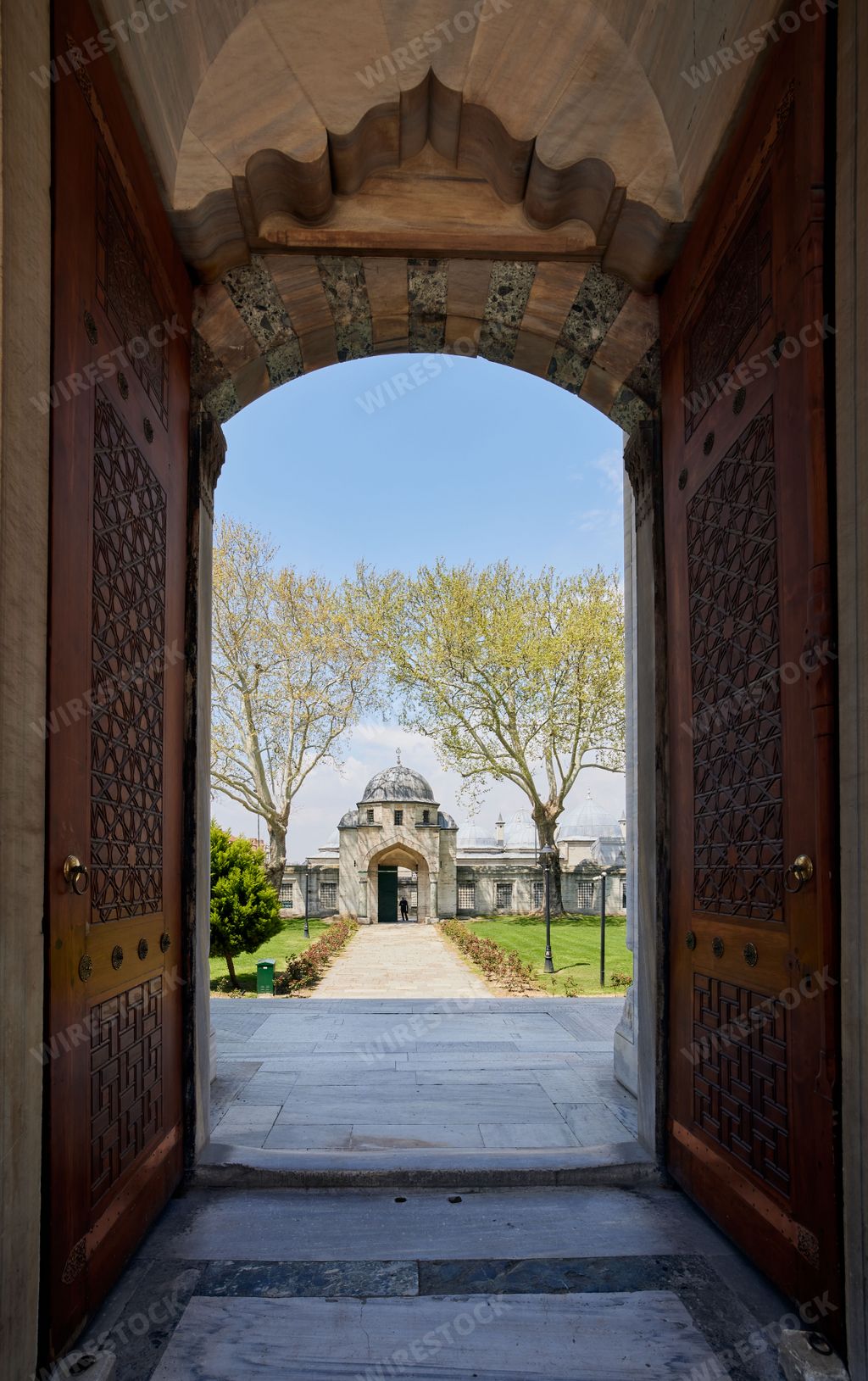 A vibrant image of two open wooden doors leading to an expansive building of Suleymaniye Mosque in Istanbul, Turkey