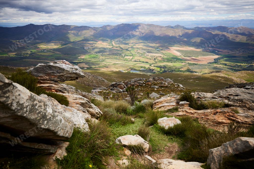 A beautiful landscape shot from rocky hill with green fields forests and mountains in the background