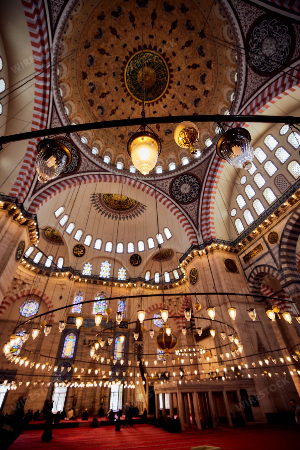 The majestic interior of a large building, featuring abundant windows and stunning arches of Suleymaniye Mosque in Istanbul, Turkey