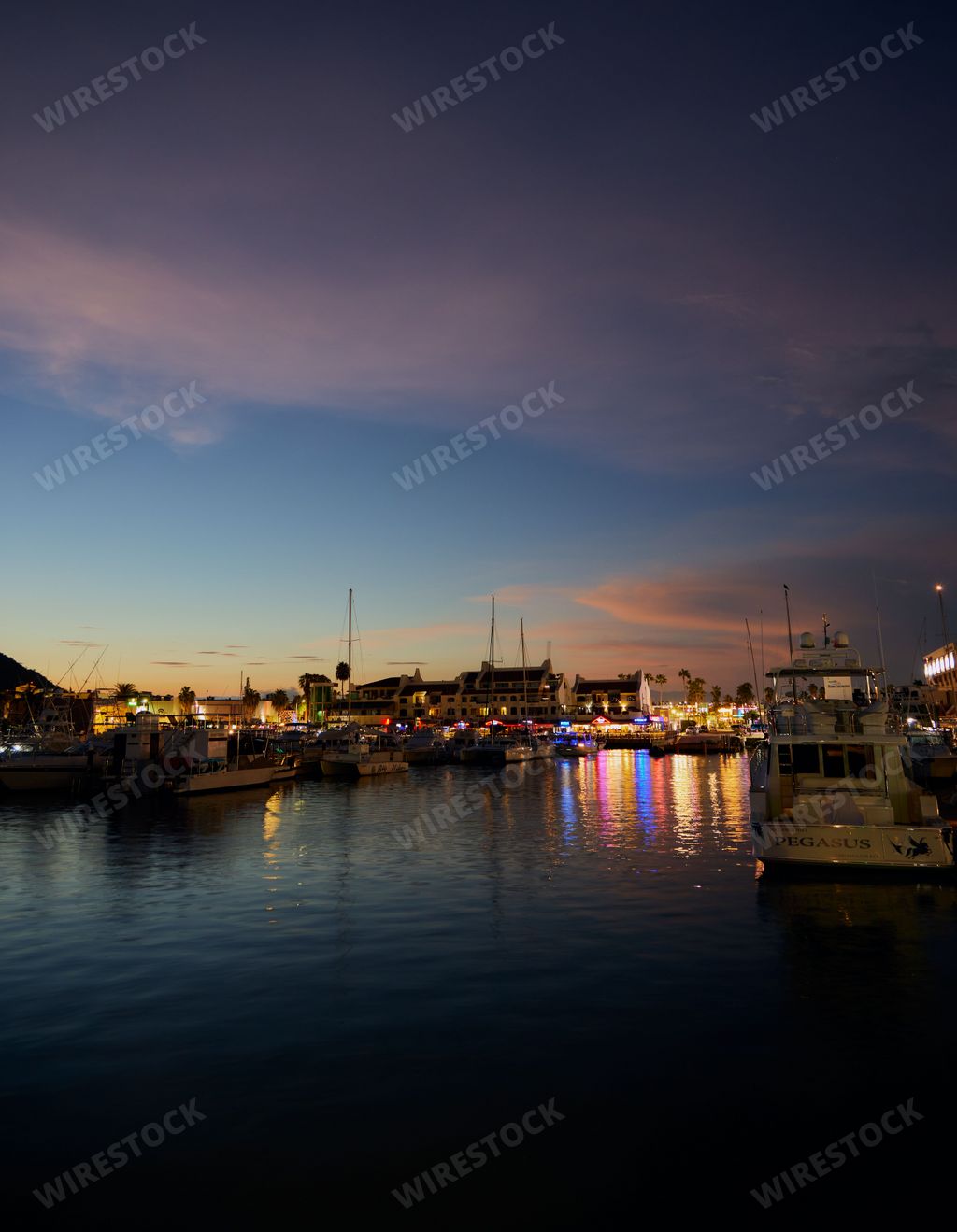 A vertical shot of sunset at the harbor with boats in Cabos San Lucas, Baja California Sur, Mexico