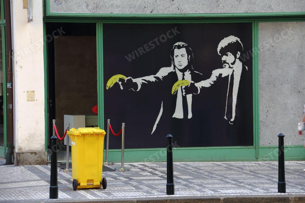 The painting of Pulp Fiction movie characters aiming at a yellow trash bin with bananas on the streets of Prague