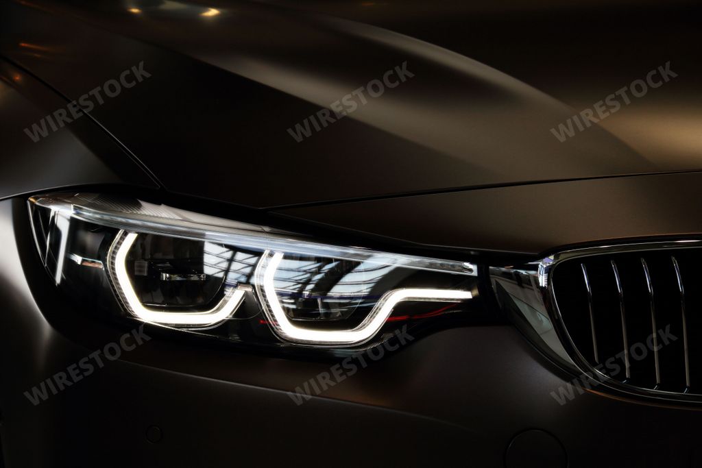 A BMW car headlight illuminated against a black background.