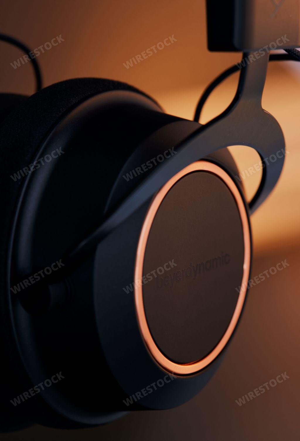 A closeup of one of the earcups of Beyerdynamic Amiron wireless headphones in an orange illuminated studio