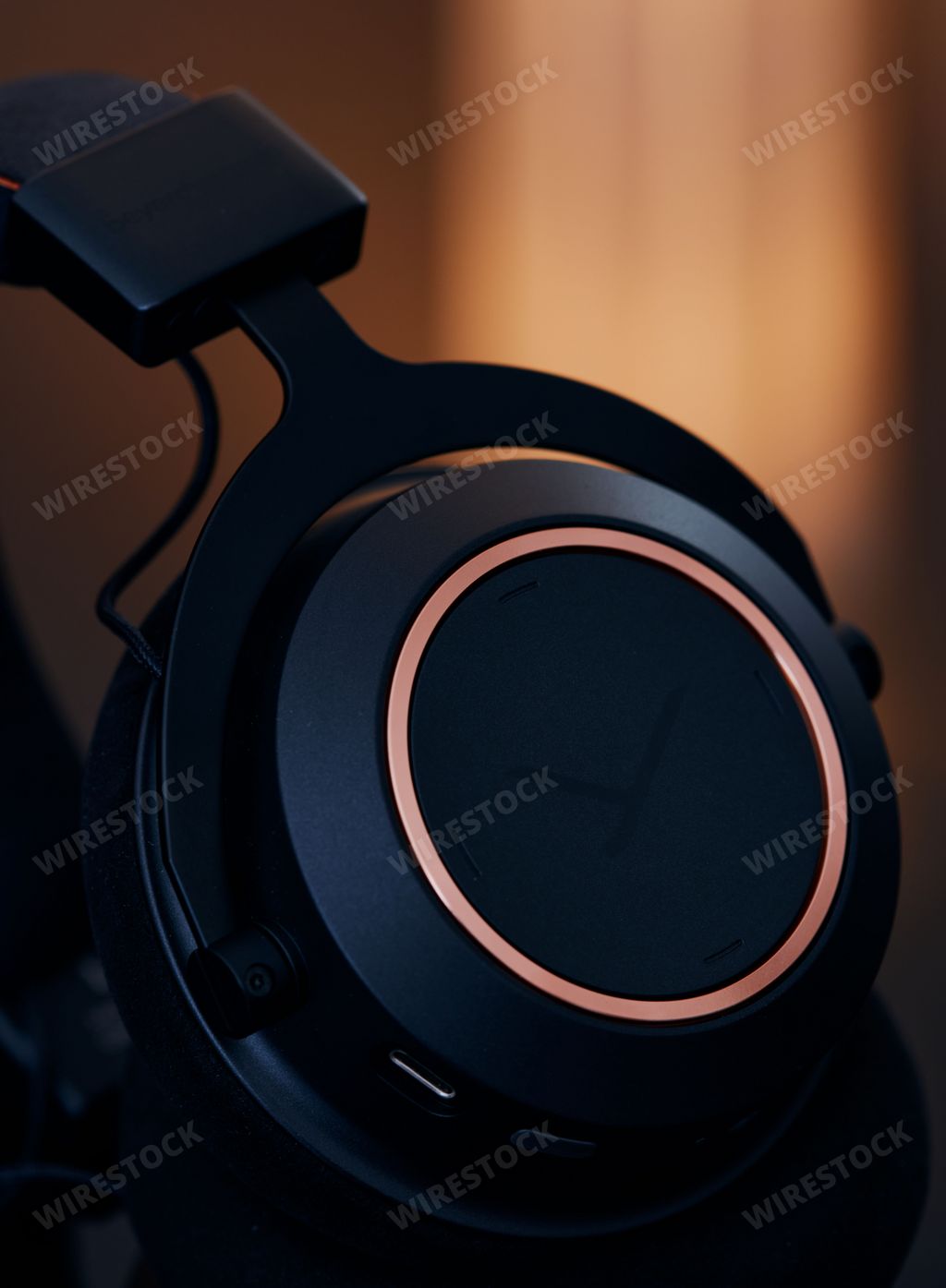 A closeup of one of the earcups of Beyerdynamic Amiron wireless headphones in an orange illuminated studio