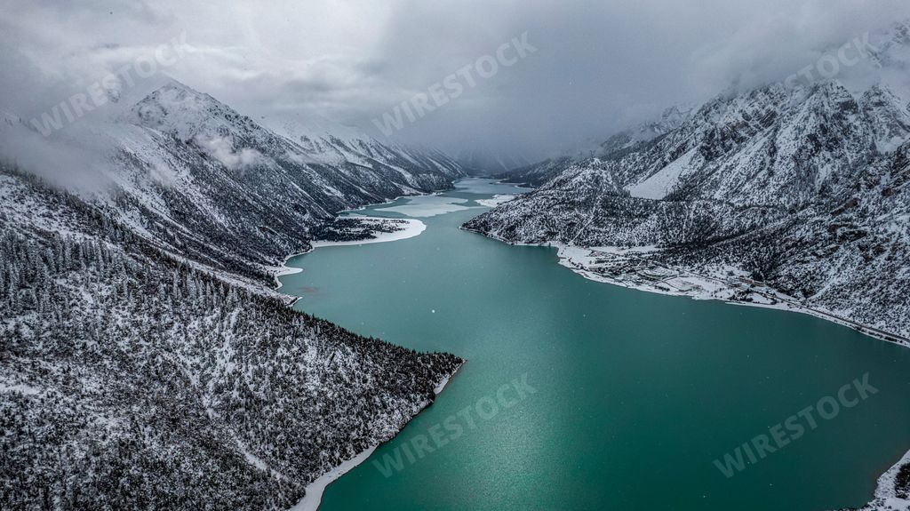 An aerial shot of the Ranwu lake in Tibet, covered with snow and surrounded by hills