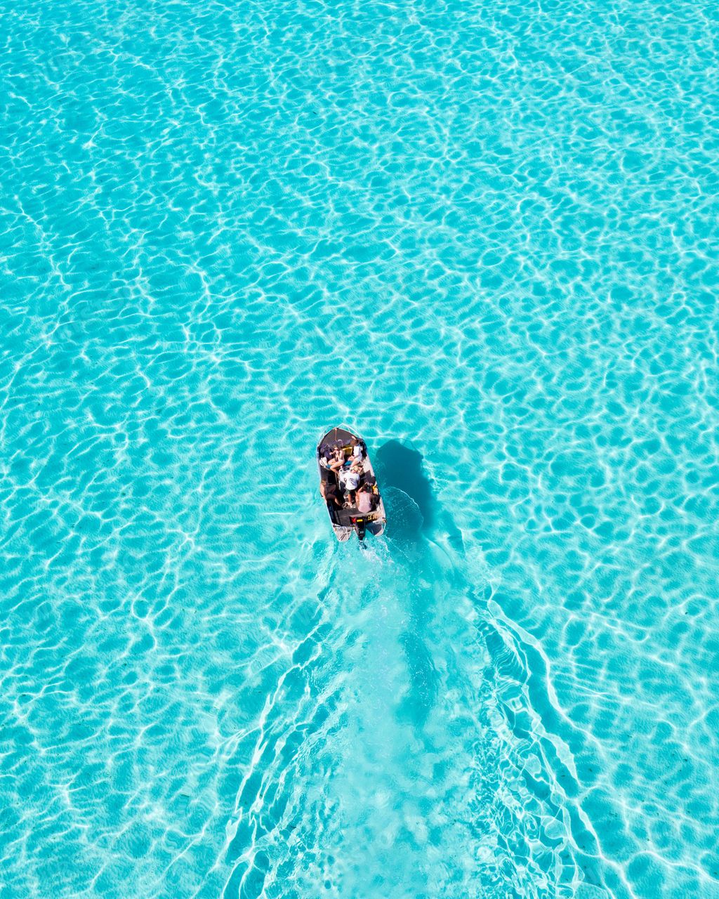 Group of tourists in a small boat rowing across tranquil lake on a sunny day, enjoying the peaceful scenery