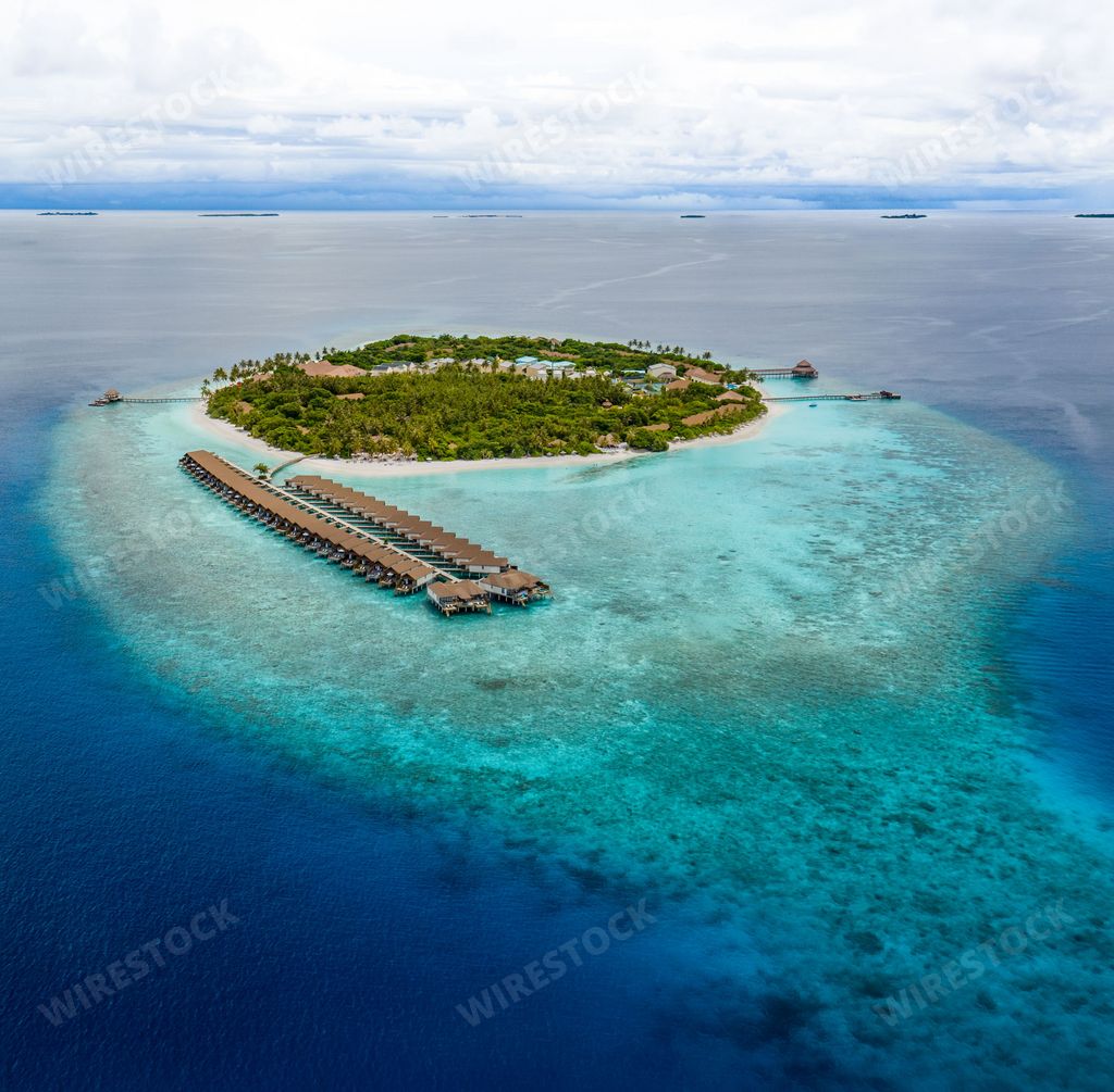 An aerial view of a tropical island with a dock in the water in the Maldives