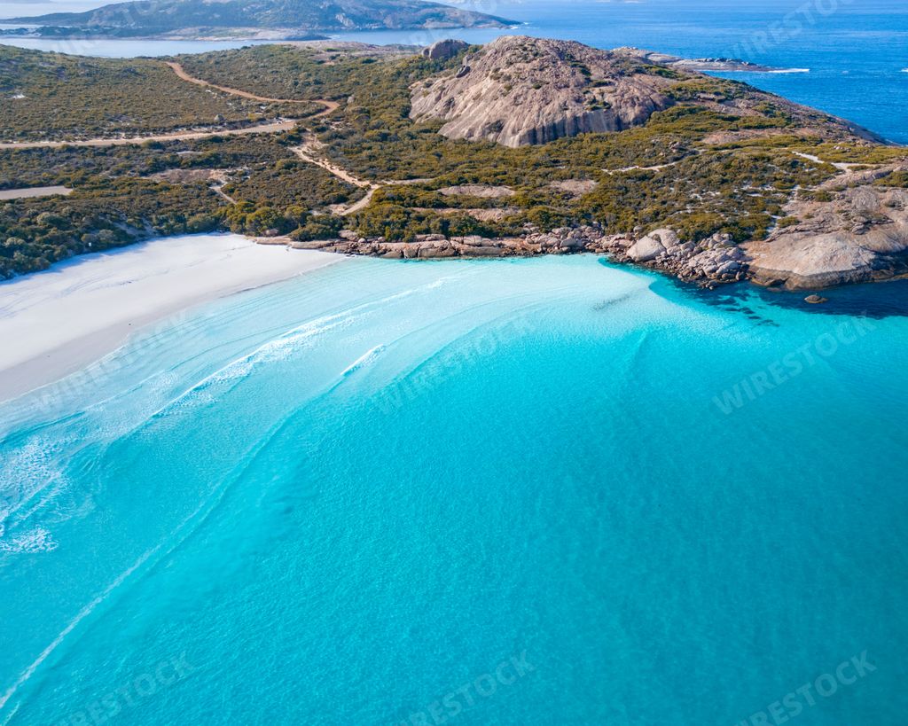 Aerial view of a pristine beach with turquoise waters and rocky terrain in Lucky Bay, Western Australia