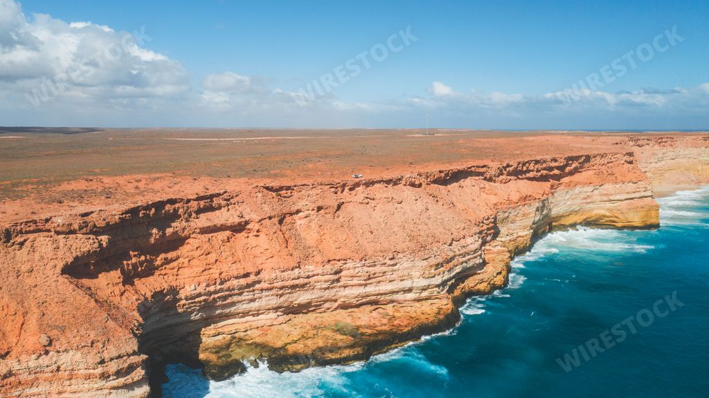 An aerial drone shot of a heavenly sandy beach with cliffs and the crystal clear ocean water