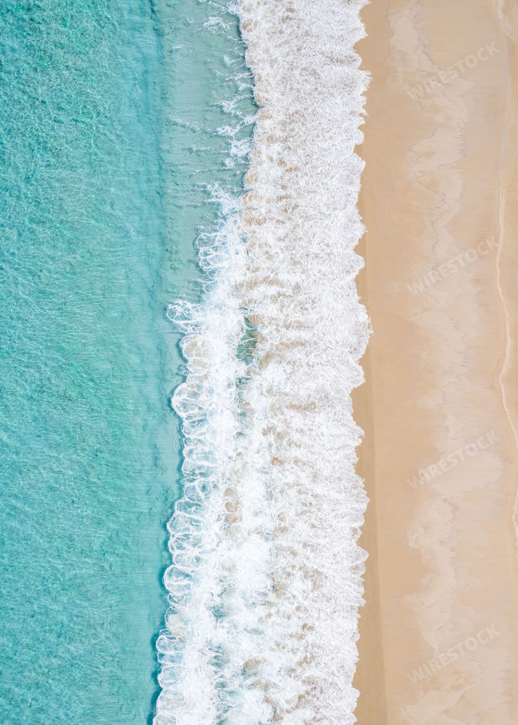 Aerial view of a sandy beach with turquoise waves crashing on the shore