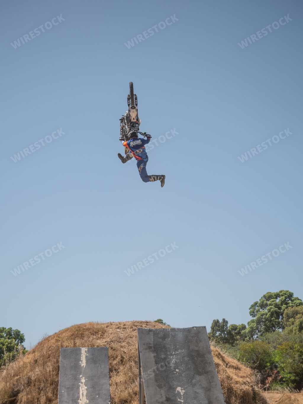 A motocross rider performing a mid-air stunt against a clear blue sky backdrop.