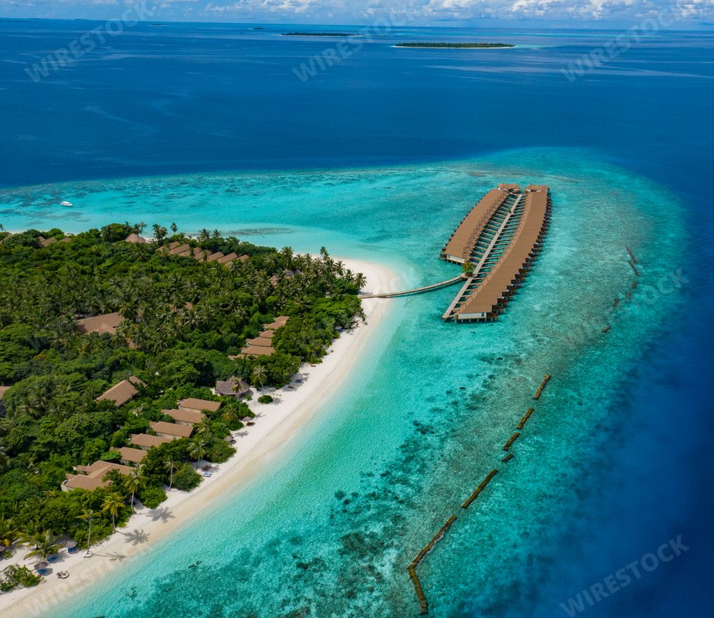 An aerial view of a tropical island with a dock in the water in the Maldives