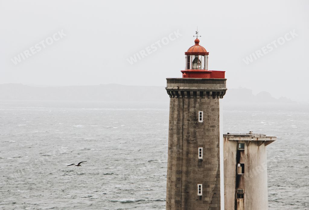 A lighthouse on the body of the sea on a gloomy day