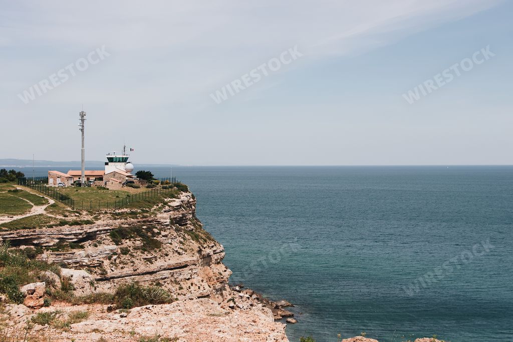 An aerial shot of a building on a big cliff on a seascape background