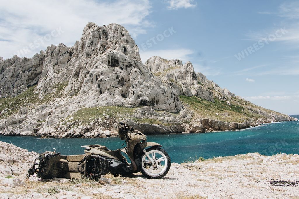 The beautiful scenery of an old motorcycle on a background of rocks and a sea in Marseille, France
