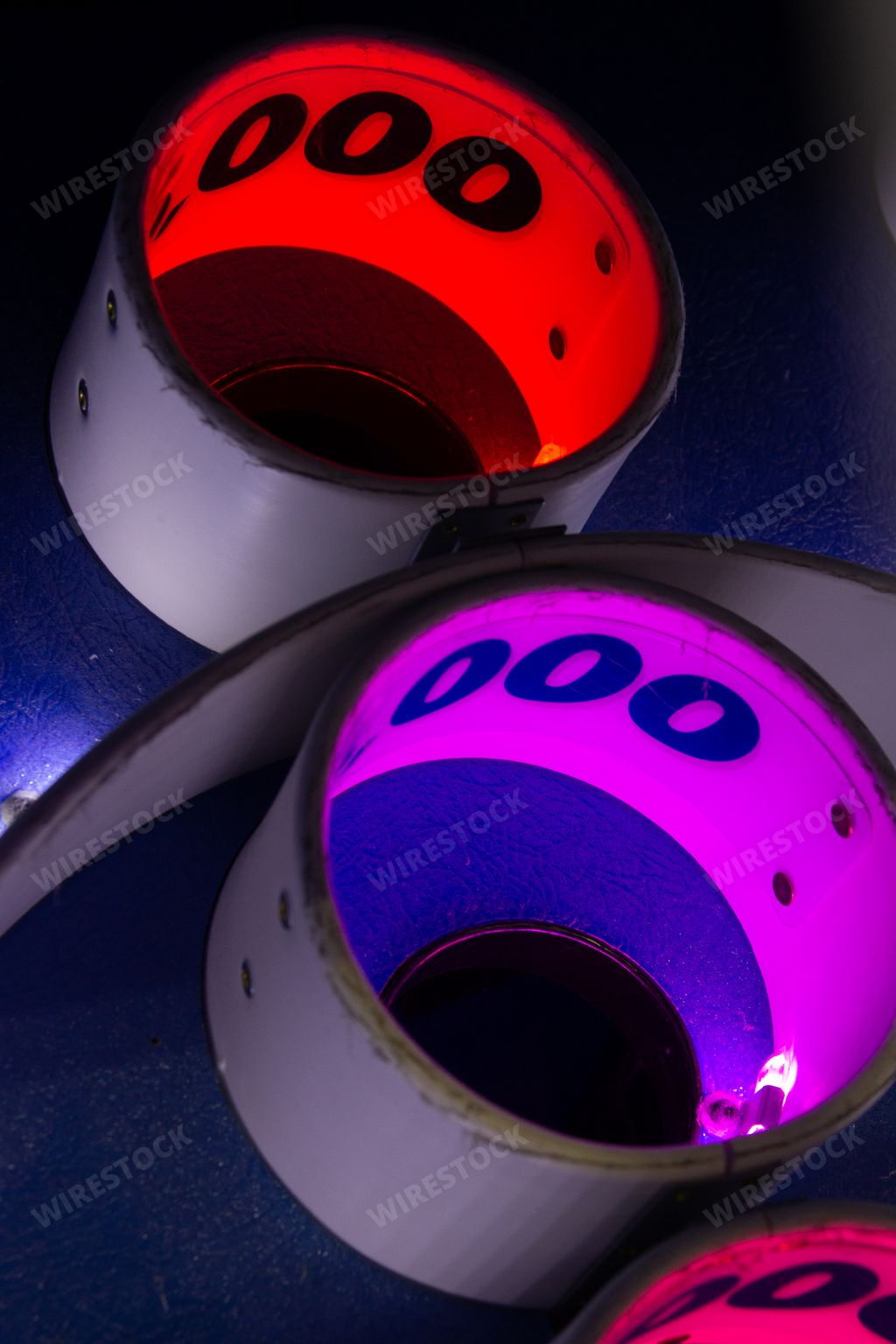 Colorful lighted holes of a Skee-Ball arcade game in a darkened arcade