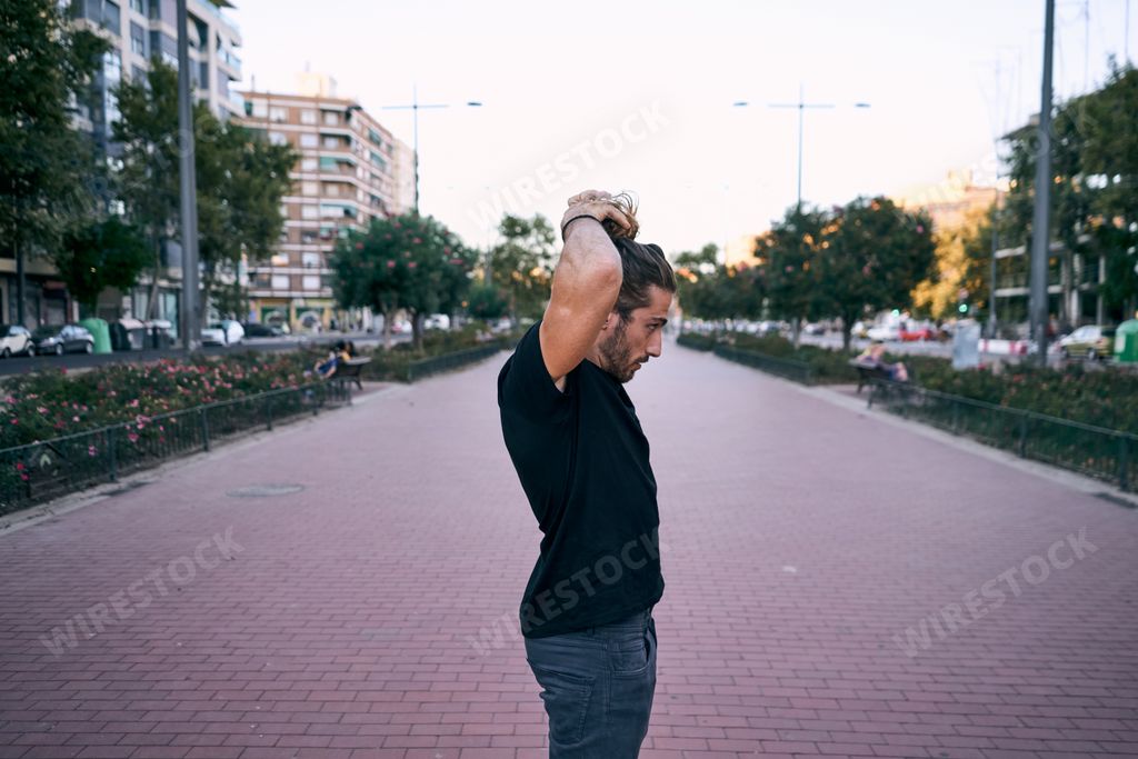 A Caucasian man untying his ponytail in the park