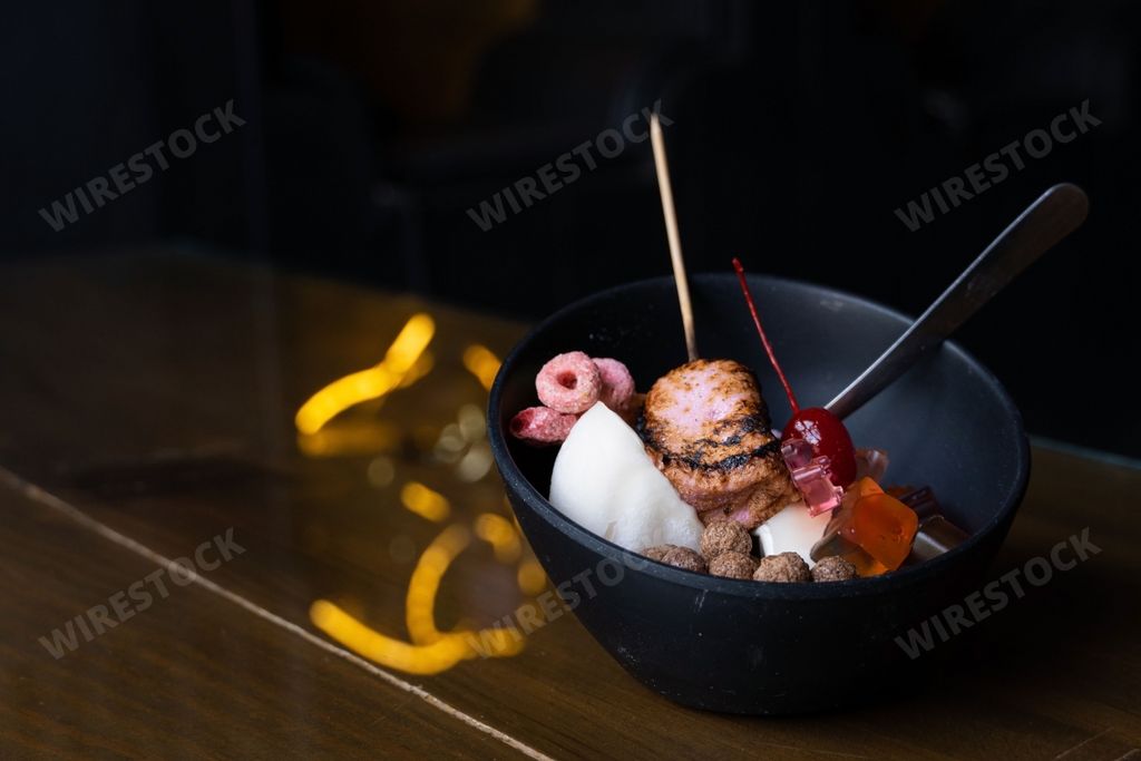 A closeup of a bowl of delicious Korean bingsu with cereal, marshmallows and gummy bears on a blurred background