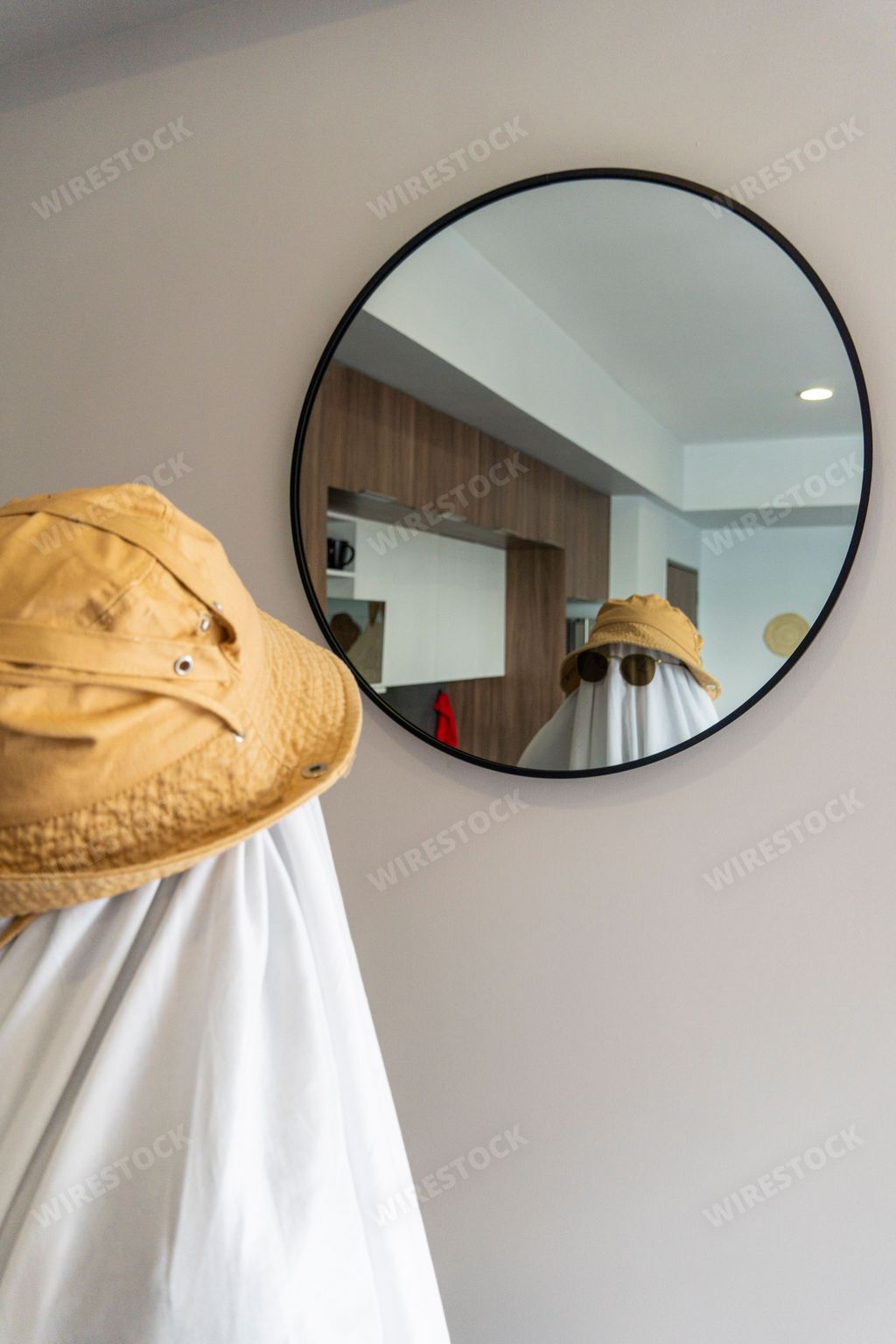 A vertical shot of a person in a funny ghost costume looking in the mirror