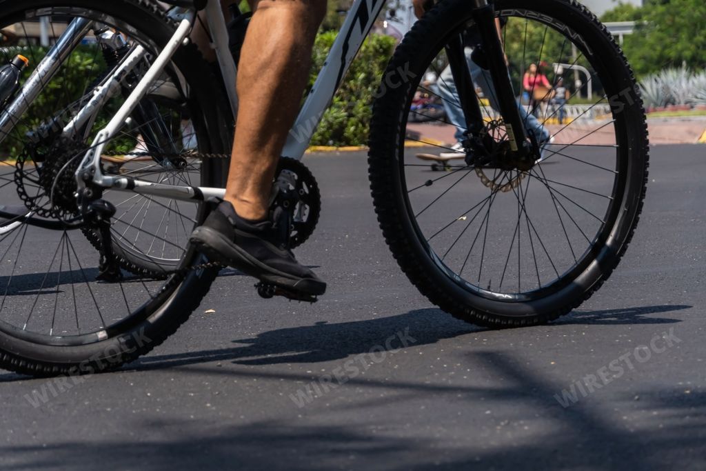 A young man riding his bicycle down the street on a sunny day