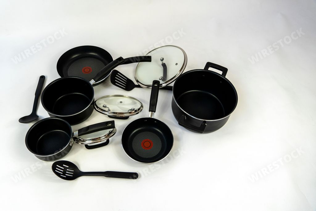 A top view of a black cookware set with plastic handles and glass lids on a white background