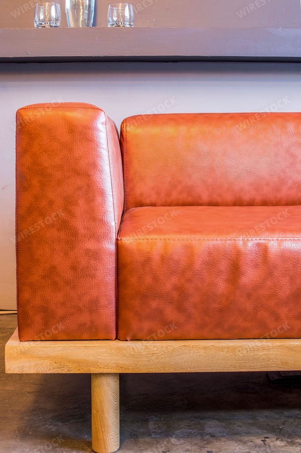 A view of a sofa made by oak wood and natural leather standing on the polished concrete floor