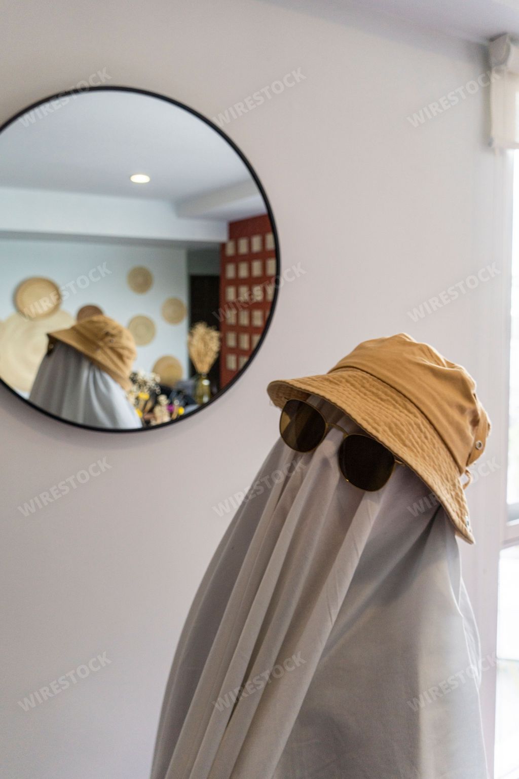 A vertical shot a person wearing a white sheet and glasses as a ghost