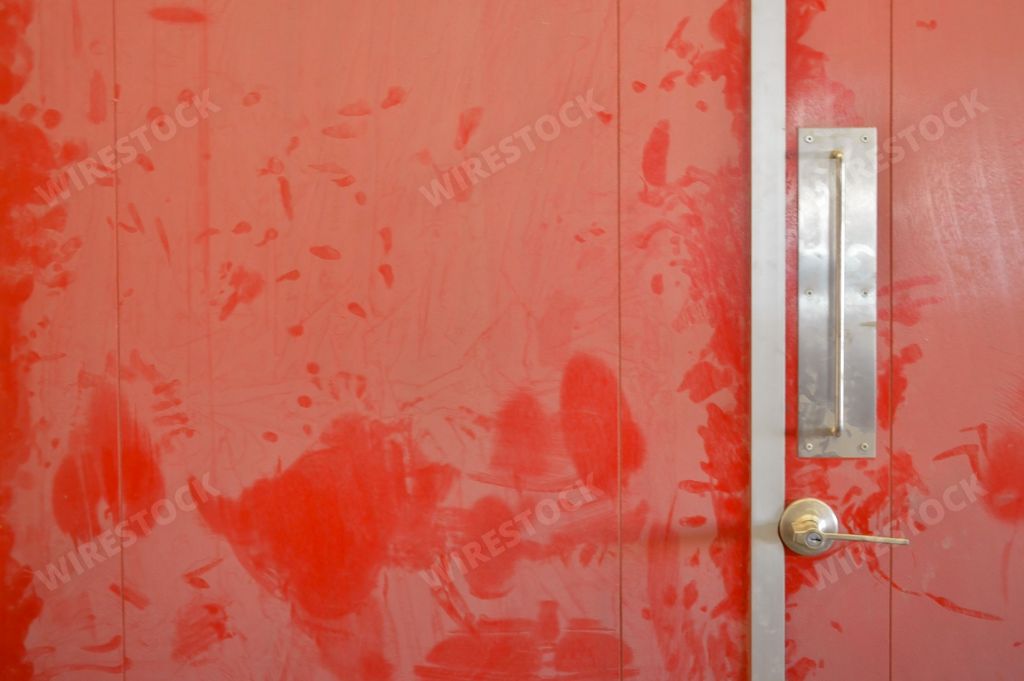 An old, dusty red wooden door with stains all over it in a factory