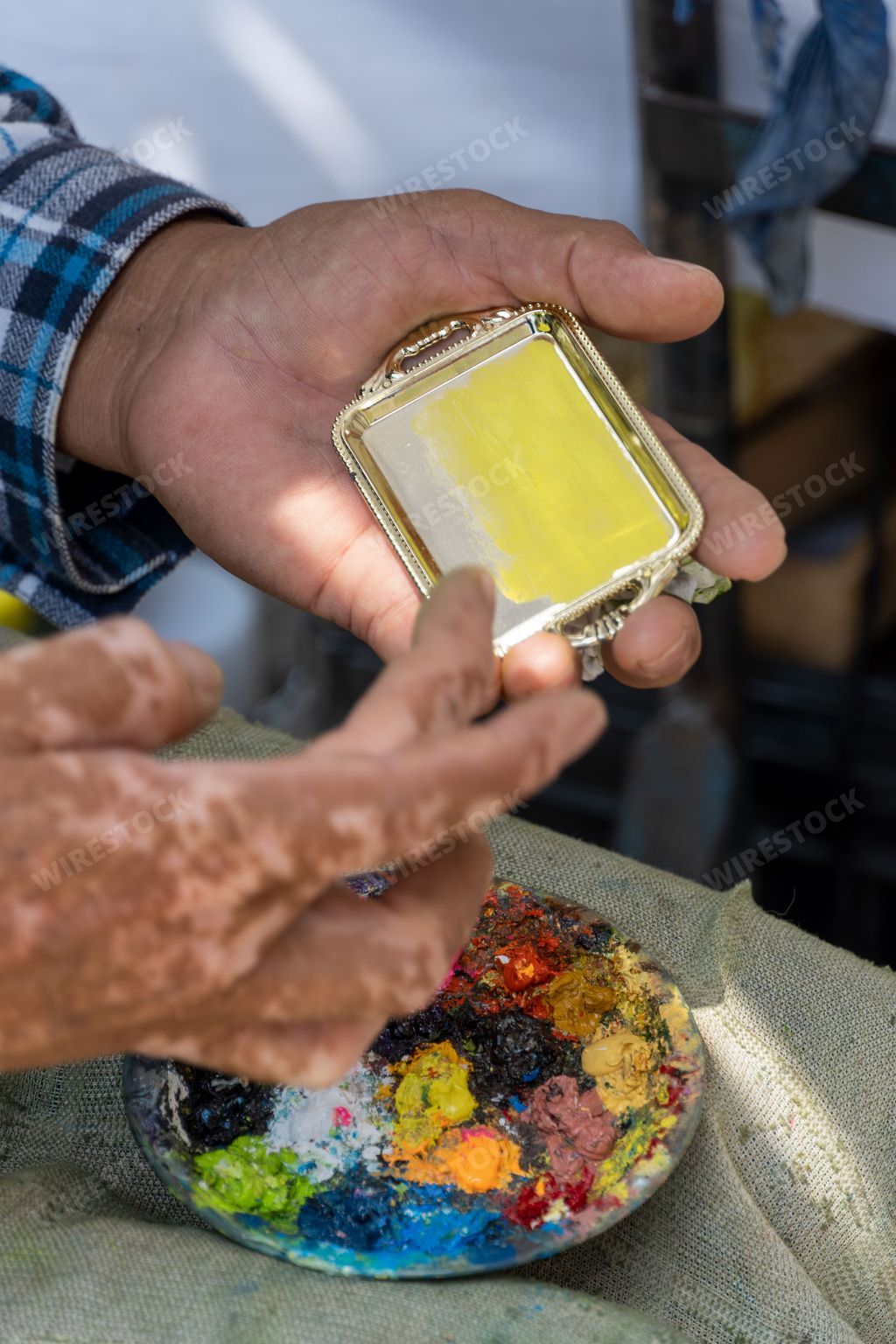 A vertical closeup of an old Hispanic man painting with his fingers on the street in Guadalajara, Mexico
