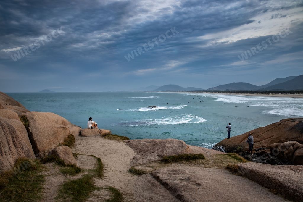 A rocky beach with people fishing and admiring the beautiful view