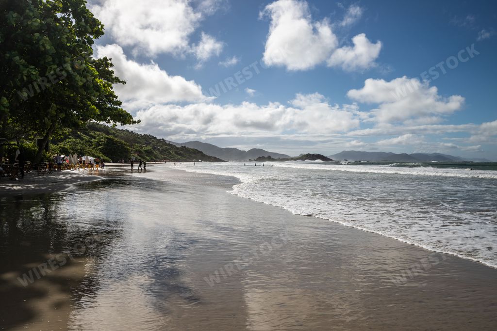 A sunny day on the beach with a cloudy sky above