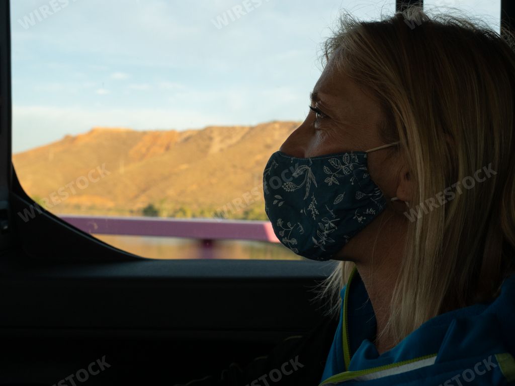 A European female with a face mask in a car - concept of new normal