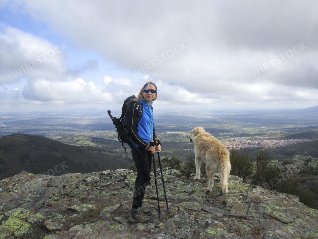 A female hiker with her dog on top of a rocky mountain