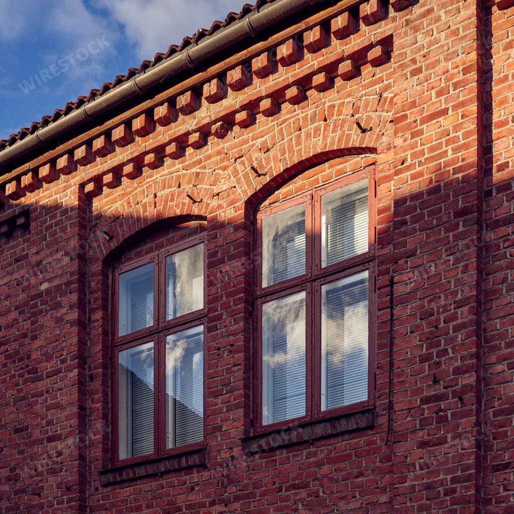 The old, vintage windows of a red brick building under the sunlight