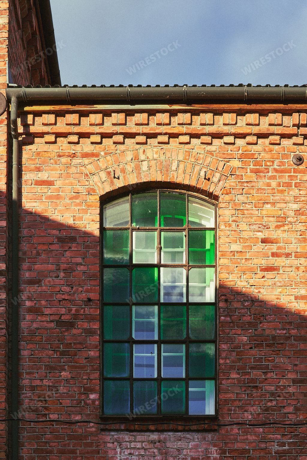 An old window of a brick wall with green, tinted glass blocks