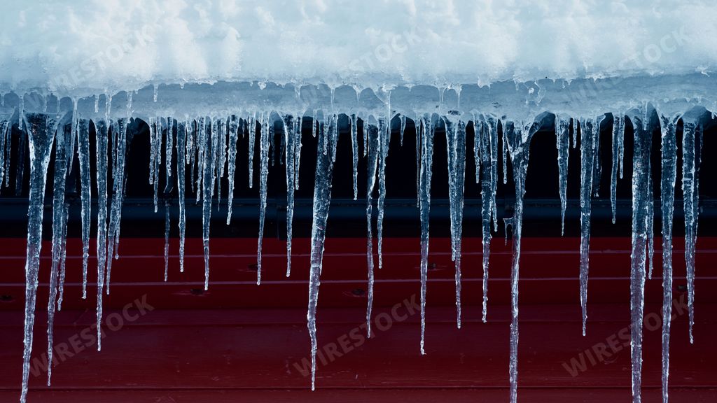 A close-up of icicles on a roof of a house in winter