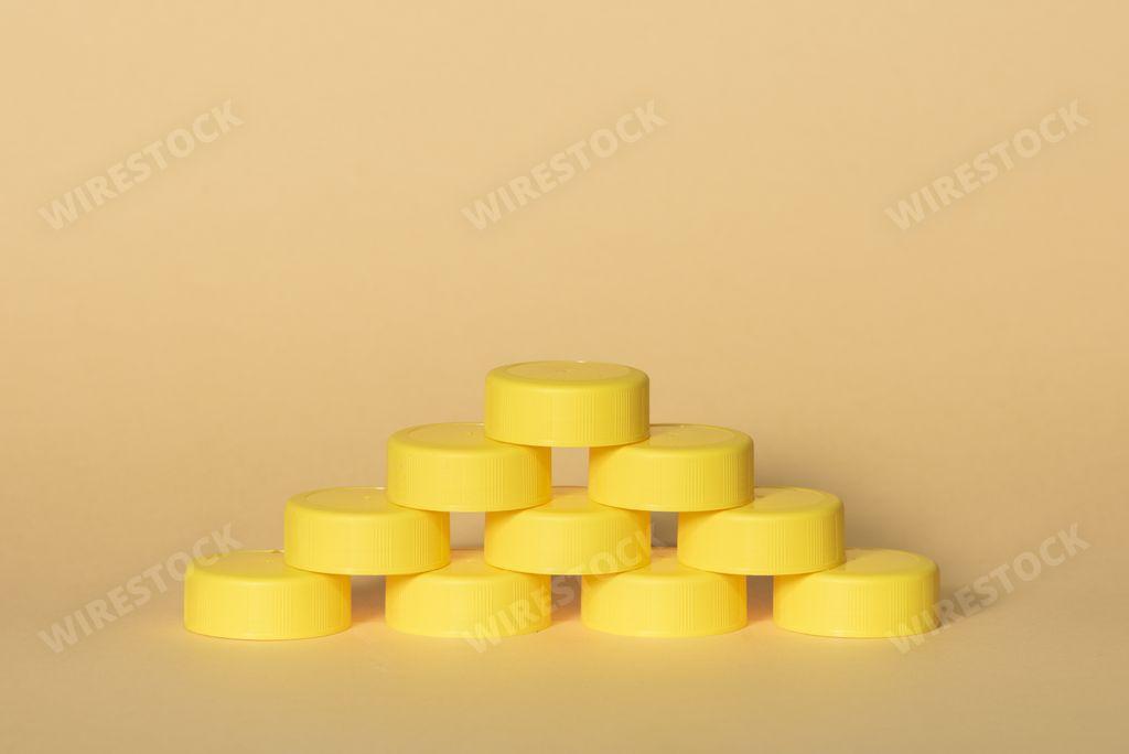 A closeup shot of yellow plastic bottle caps forming a pyramid