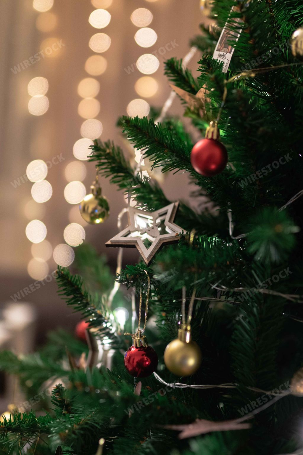 A vertical closeup shot of a decorated Christmas tree with a blurry festive lights background