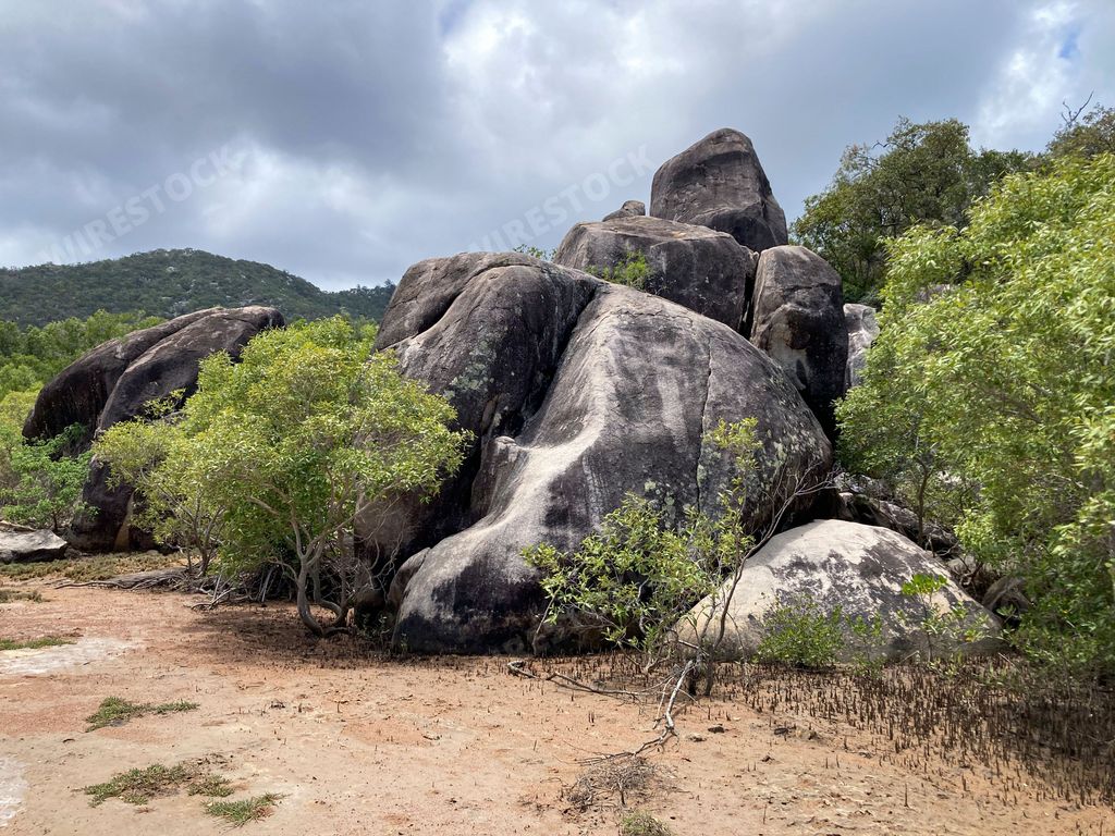 A majestic rocky outcrop with a cluster of trees on either side in Cockle Bay on Magnetic Island in Townsville, Australia